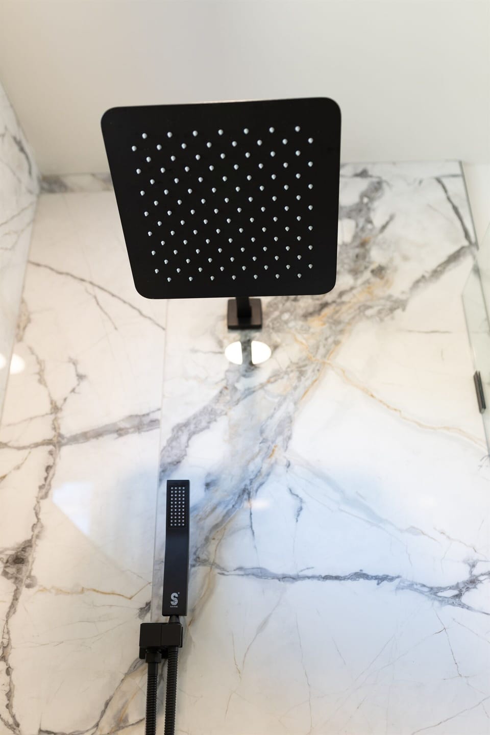 Main House Bottom Unit En-Suite Bathroom #1 with floor to ceiling porcelain tile, walk-in shower with oversized rainfall shower head and handheld shower feature, large in-shower window and vanity,