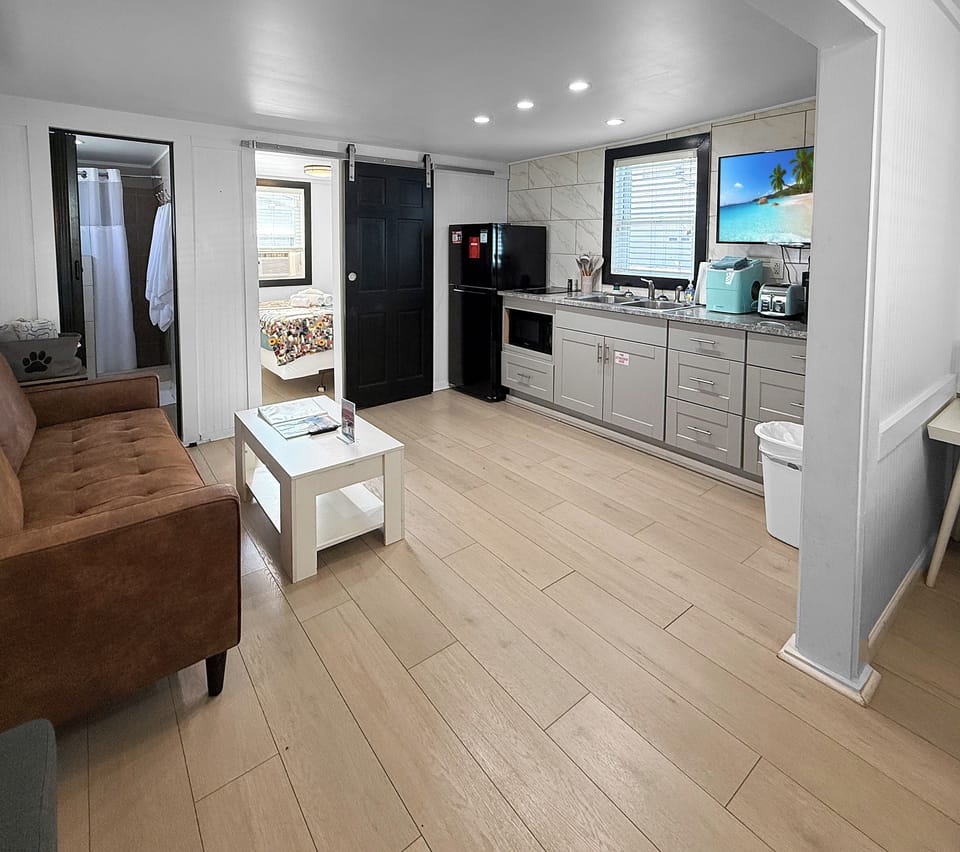 View of main room with leather sofa, kitchen, bathroom and private bedroom