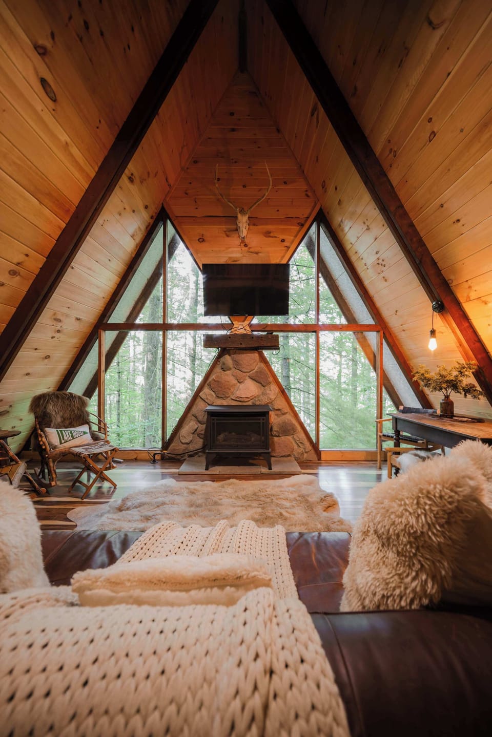 A-frame Living Room: Relax by the fireplace with stunning woodland views and stylish decor!