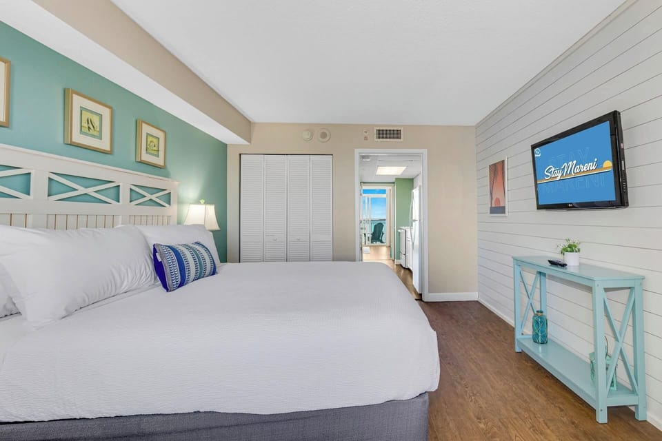 Relax in style in this serene bedroom featuring a plush king-sized bed, soothing coastal decor, and ample natural light. Drift off to the sound of the waves and wake up refreshed, just steps away from breathtaking ocean views. 