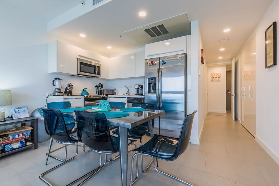 Your sleek, modern kitchen flows into a bright dining space, complete with stainless steel appliances, cheerful teal accents, and everything you need to cook and share meals together.