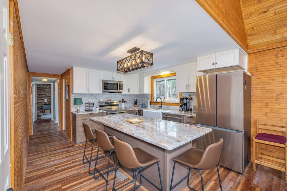 Newly renovated kitchen shines with stainless Samsung appliances, Dolomite countertops, large farm sink, icemaker, and counter seating for 4.