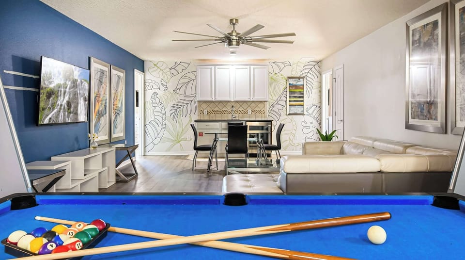 Colorful loft with pool table, TV, modern art, and tropical wall accents.