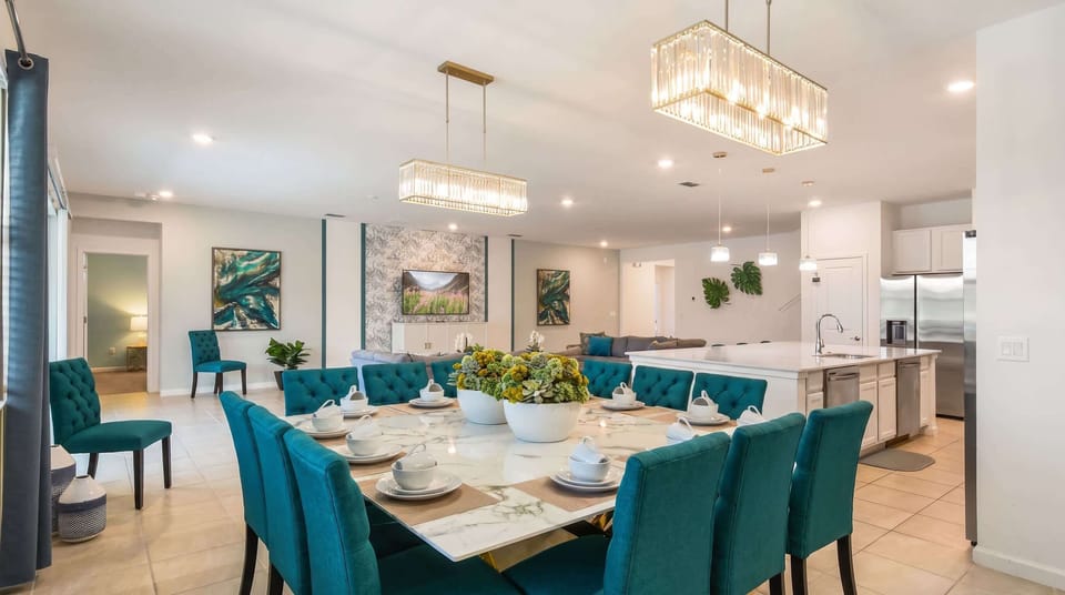 Elegant open-concept dining area with a marble table, plush seating, and chic lighting!