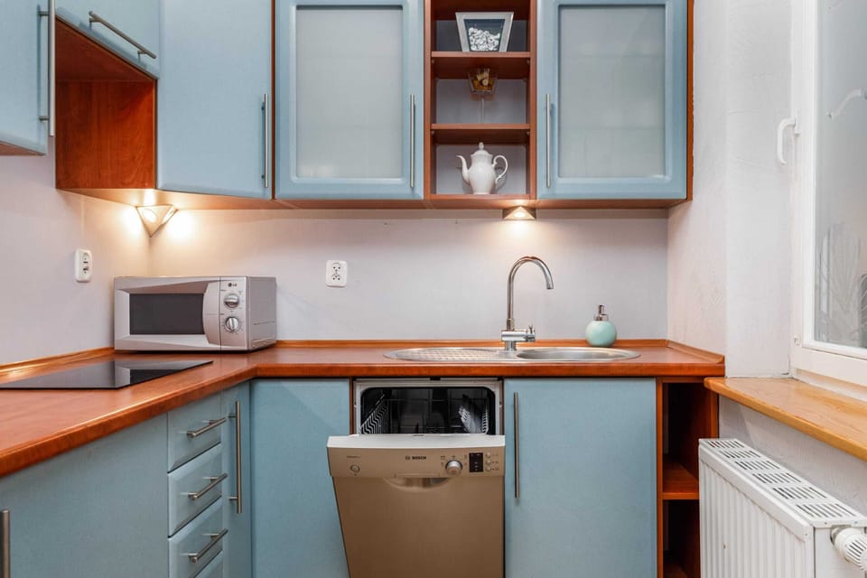 A compact and stylish kitchen with blue cabinets, wooden countertops, and modern appliances.
