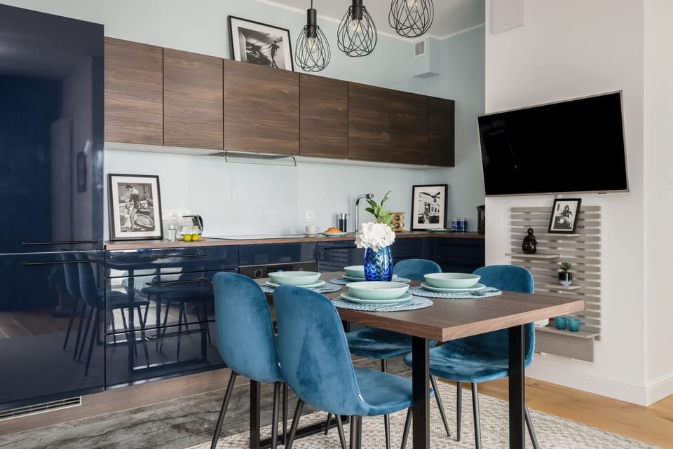 Kitchenette with electric hob, oven, fridge with freezer, electric kettle, coffee maker, microwave, dishwasher and table with chairs.