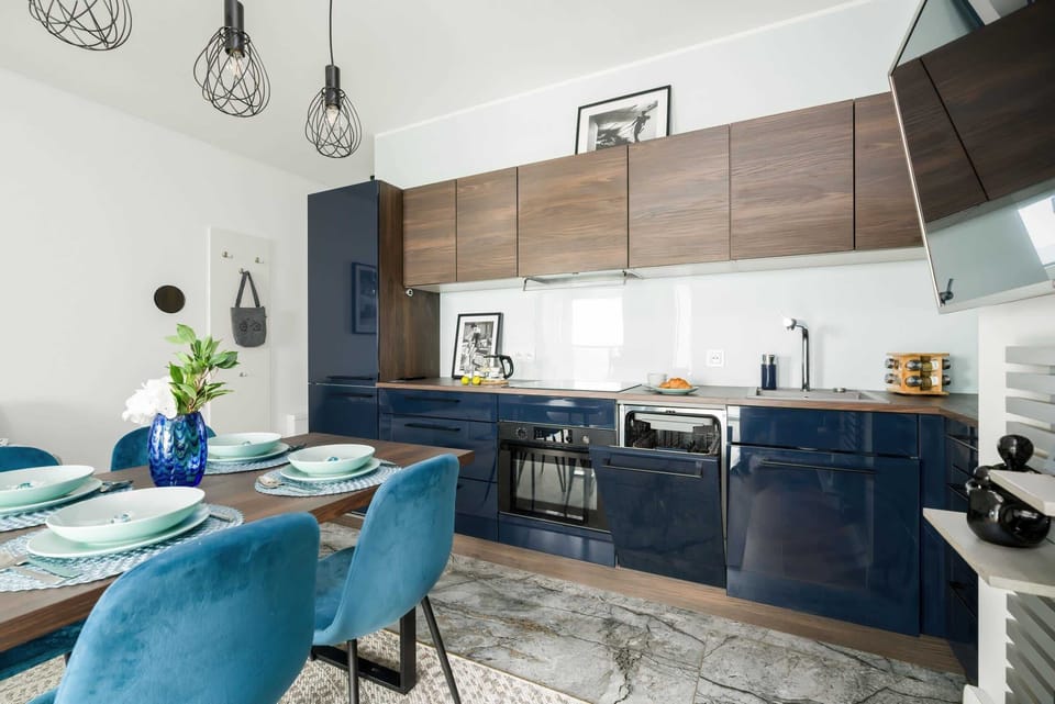 Kitchenette with electric hob, oven, fridge with freezer, electric kettle, coffee maker, microwave, dishwasher and table with chairs.