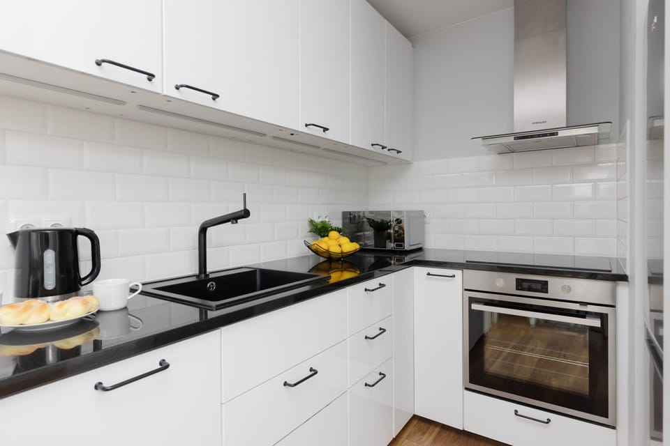 A modern kitchen with white cabinets and sleek appliances. The backsplash is made of white subway tiles, and the countertop features lemons and small decor, giving it a fresh look.