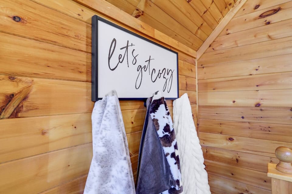 A large "Let's Get Cozy" sign, adorned with three incredibly soft blankets hung below, serves as beautiful decor and a warm welcome for our guests. Along with super soft blankets throughout the cabin, it ensures ultimate comfort during your stay!