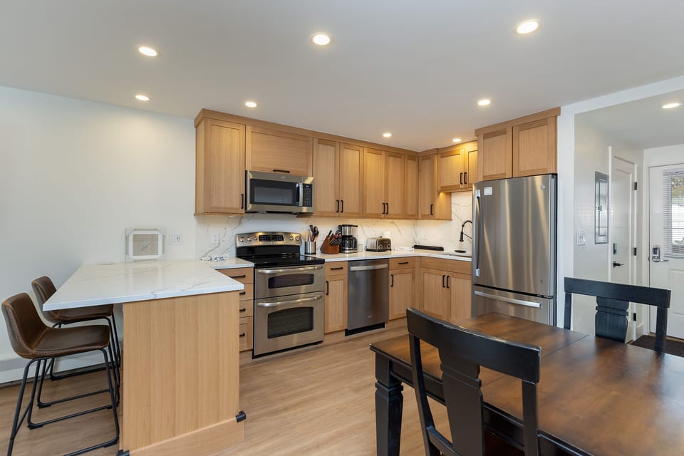 Your fully equipped kitchen features warm wood cabinetry, stainless steel appliances, and a breakfast bar perfect for morning coffee.
