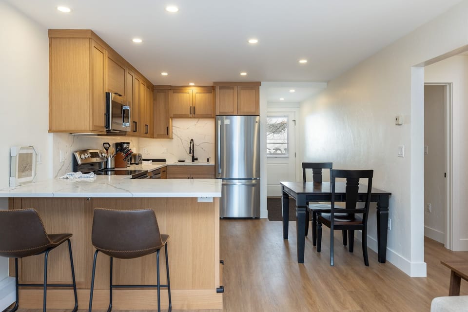 Your modern kitchen features warm wood cabinets, stainless steel appliances, and a breakfast bar perfect for morning coffee or casual meals.