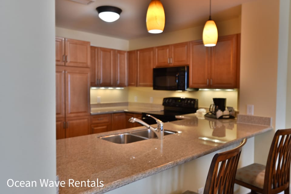 Modern kitchen with granite, warm wood cabinets, and stylish pendant lighting.