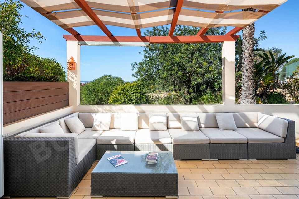 Covered terrace with comfortable lounge seating and garden views at Boa Nova 30/1, near Carvoeiro, Algarve