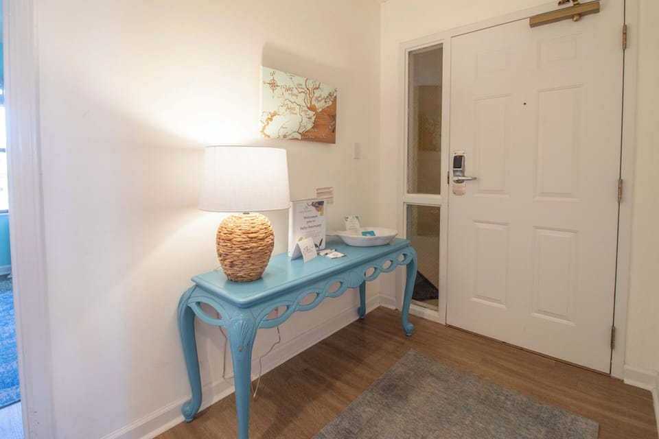 Step into your welcoming entryway featuring a charming turquoise console, warm woven lamp, and thoughtful coastal touches that set the tone for relaxation.