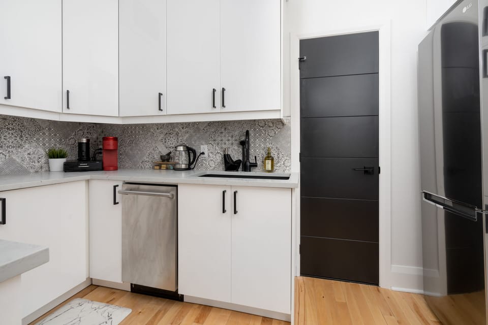The white/black bathroom is located in the kitchen behind this black door.