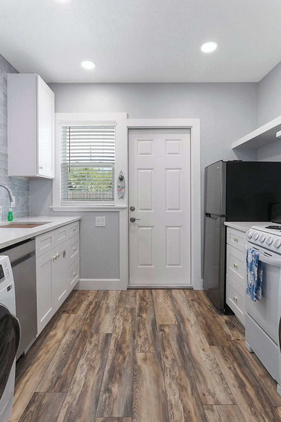 Fully equipped kitchen with apartment-size appliances.  Kitchen sink, 18" stainless steel, dishwasher, coffee maker, Keurig coffee maker, 24" clothes washer & dryer, 20" 4 burner range/oven, and 10 cu ft refrigerator.  The back door to the kitchen le