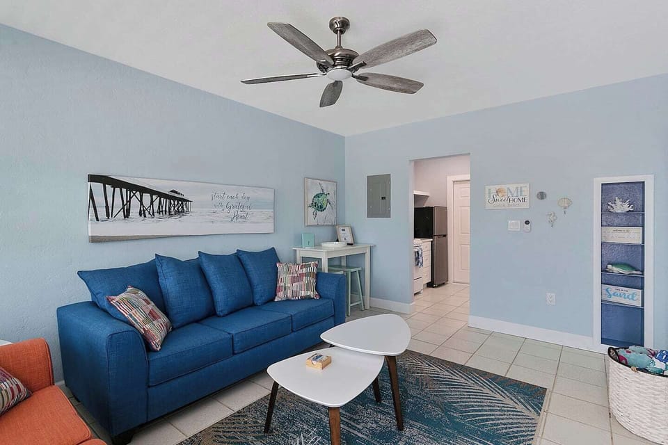 Cute Beach Decor! Great room with sleeper sofa, love seat, dining table with 2 stools, and 53" Smart TV with Hulu streaming service, basket with beach towels.