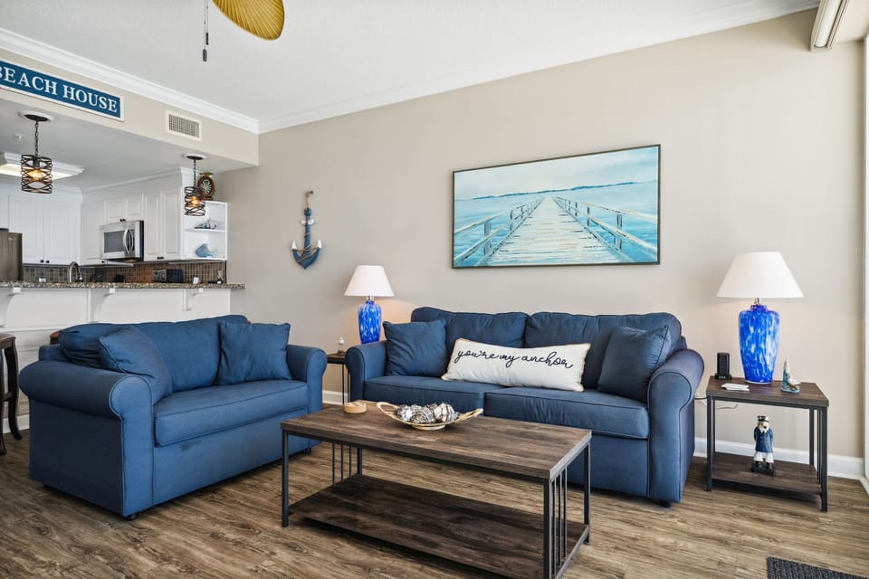 Living room offers ample, comfortable seating with flat screen television, gulf views, and a door leading to the unit's private balcony.