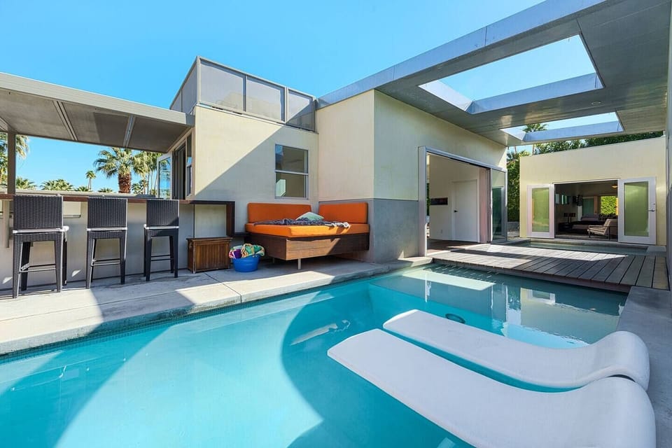 Unwind by the pool with bar seating, a full outdoor kitchen, and a cozy daybed for the ultimate lounging experience.