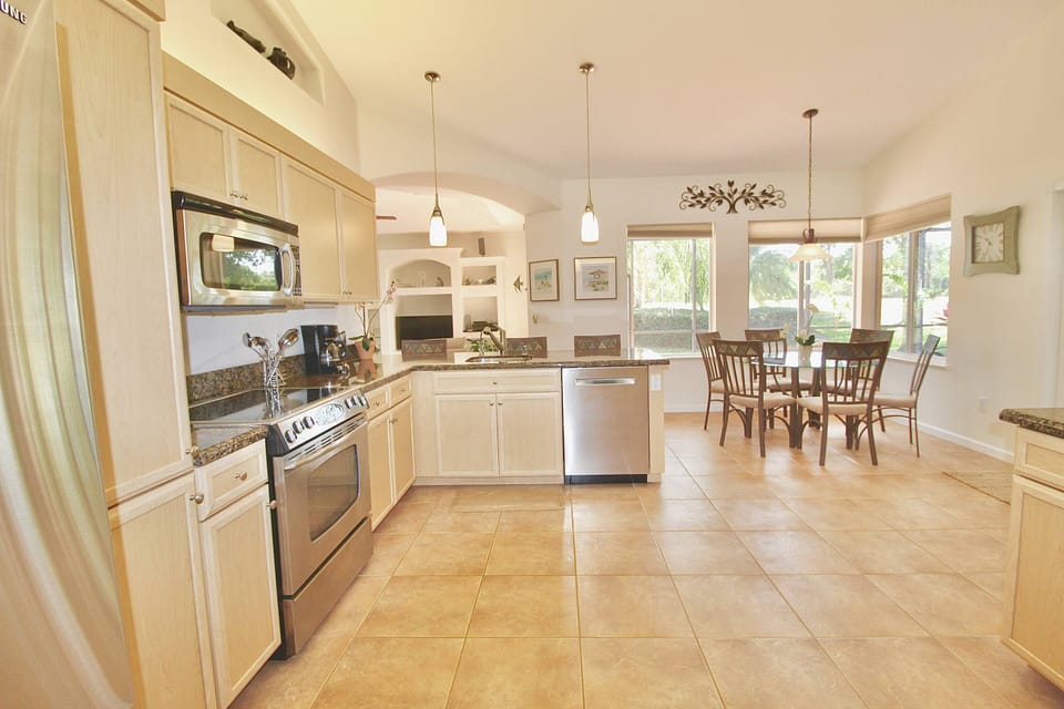 The spacious, fully stocked open kitchen has stainless steel appliances & granite countertops.