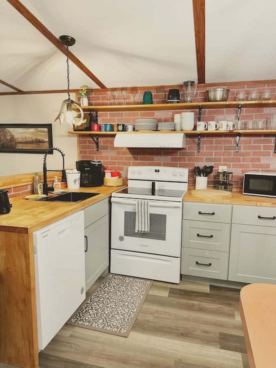 Fully stocked with all your cooking and dining essentials, this kitchen boasts exposed shelving, a dishwasher, microwave, and a Keurig & drip coffee maker combo—with coffee included!