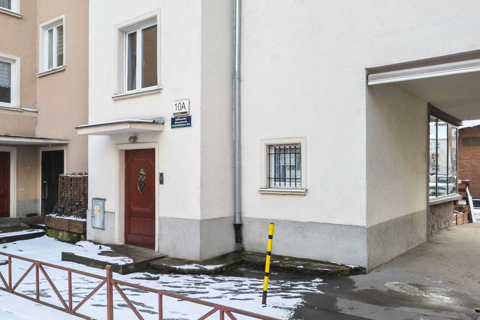 An exterior shot of the apartment building's entrance, surrounded by quiet streets.
