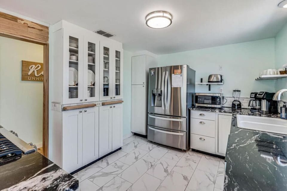 Spacious kitchen with stainless steel fridge, granite counters, and appliances.