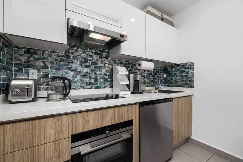Your sleek modern kitchen features glossy teal backsplash tiles, stainless appliances, and everything you need to whip up delicious meals during your stay.