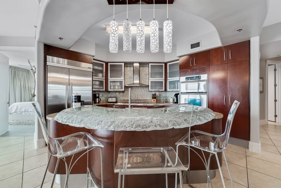 Exquisite details abound in this high-end kitchen, from the frosted glass cabinetry to the professional-grade appliances. Experience luxury in every culinary creation.