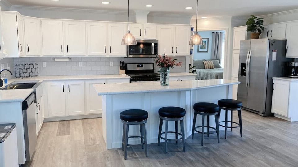 Large kitchen with new whirlpool appliances and four barstools.