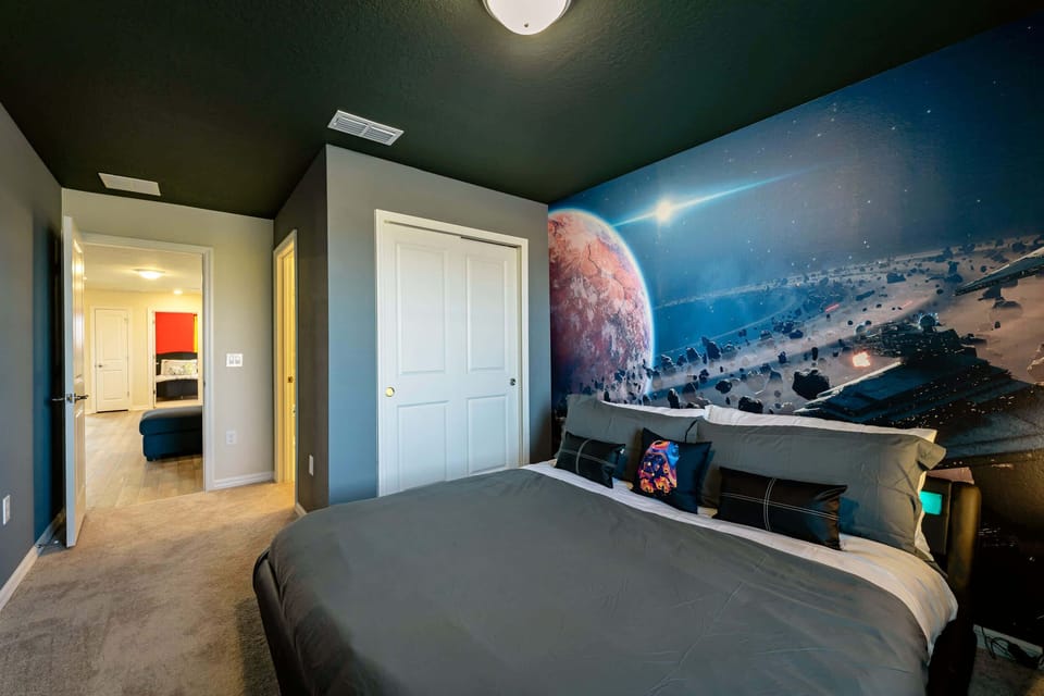 Private bedroom with a comfortable king-size bed and an immersive outer-space mural featuring planets, stars, and a spacecraft.