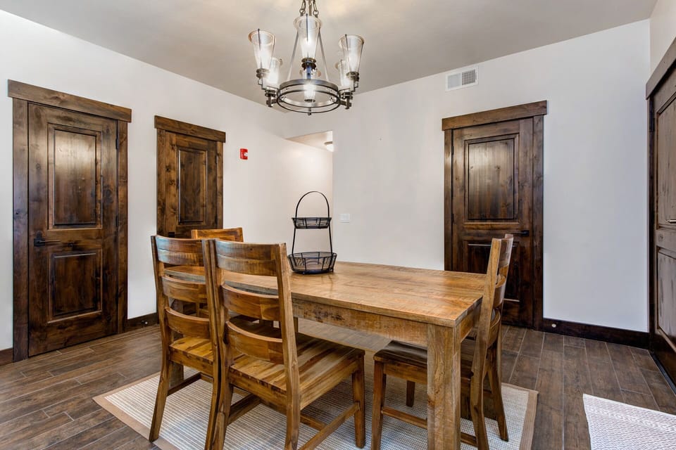 This inviting dining area features a solid wood table with bench seating and is situated near two large closets for convenient storage. The warm tones and soft lighting create a cozy, functional space for meals and conversation.