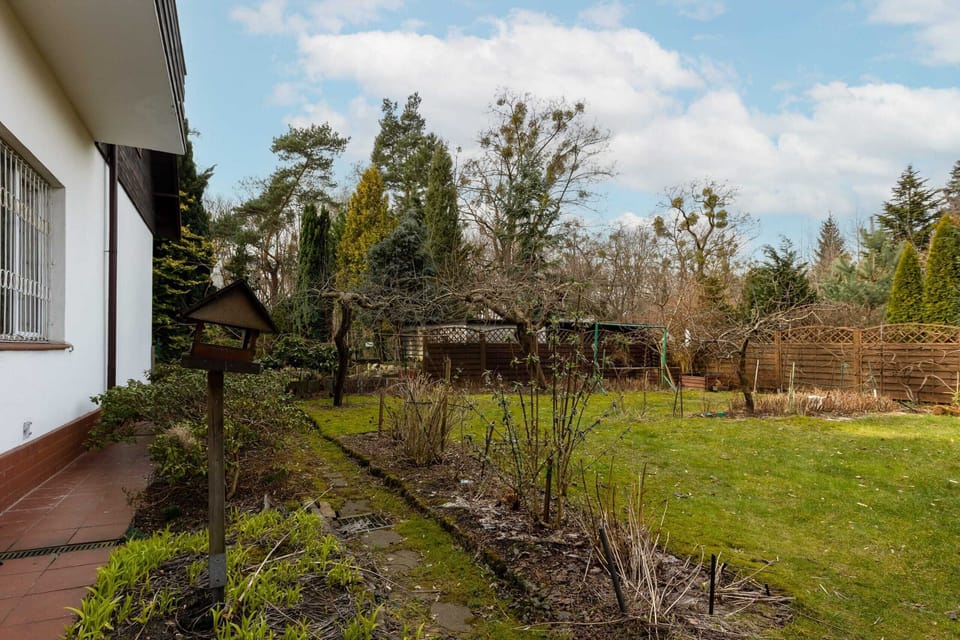 An expansive garden with neatly arranged flower beds, trees, and a tranquil atmosphere.





