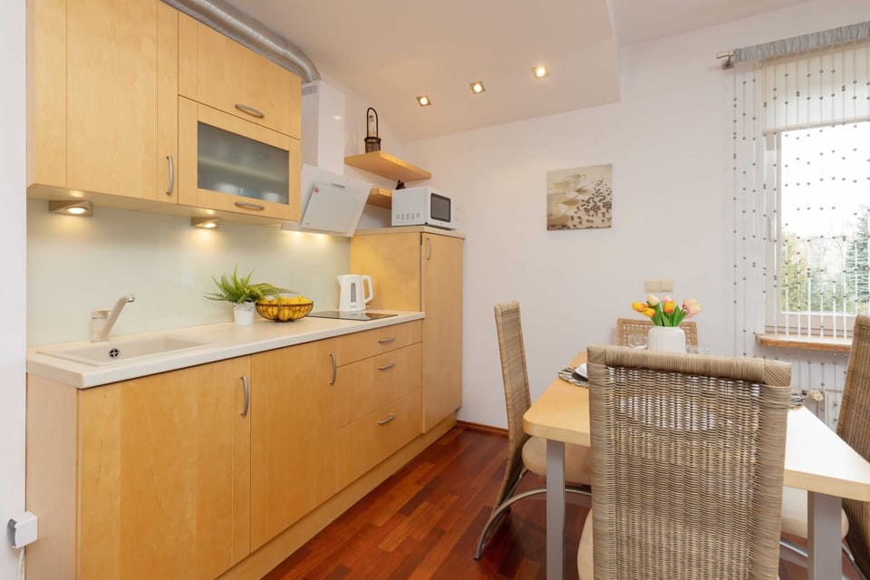 A kitchen with wooden cabinets, modern appliances, and a dining table for four.
