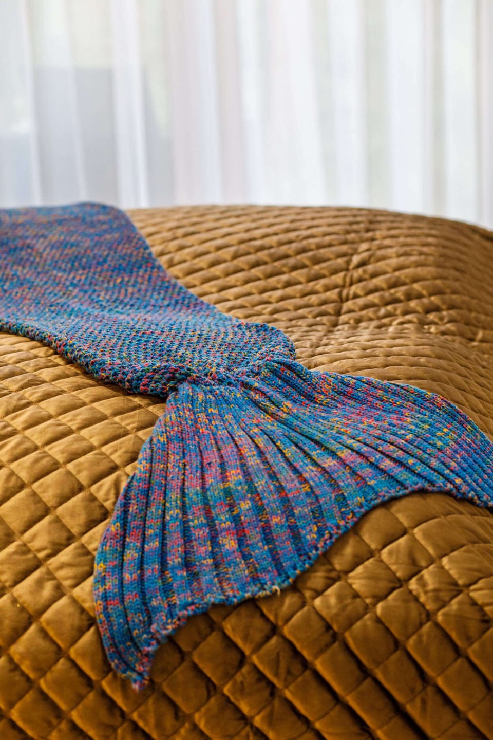A close-up of the bed with textured covers and a vibrant blue throw blanket.
