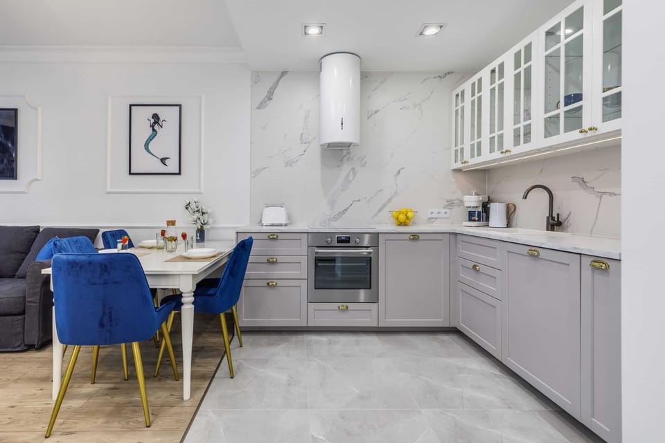 A modern kitchen with grey cabinets, a marble backsplash, and bright lighting for a clean, sleek look.
