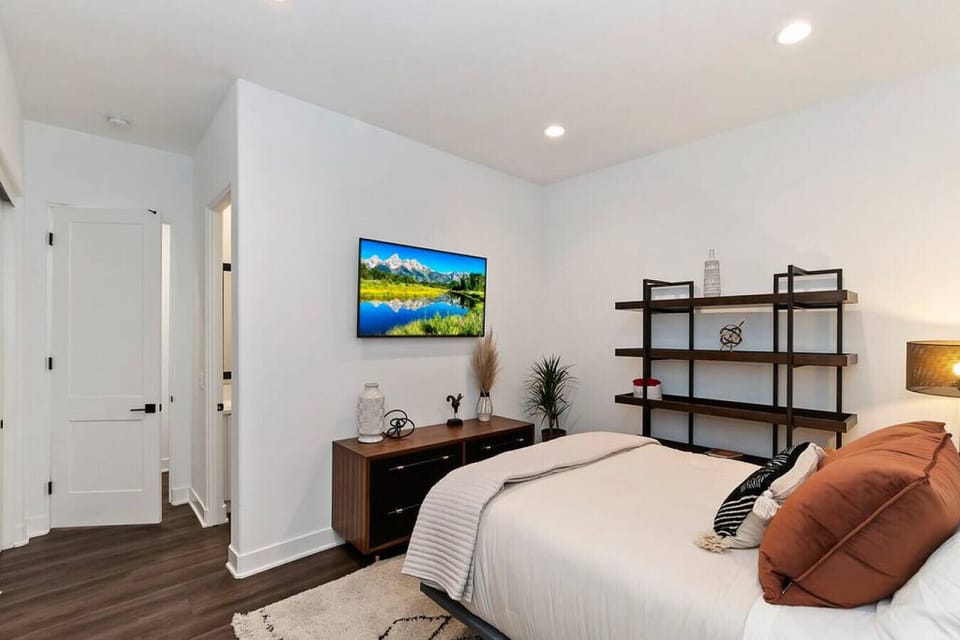 Minimalist bedroom w/ mounted TV, clean lines & a peaceful, airy atmosphere