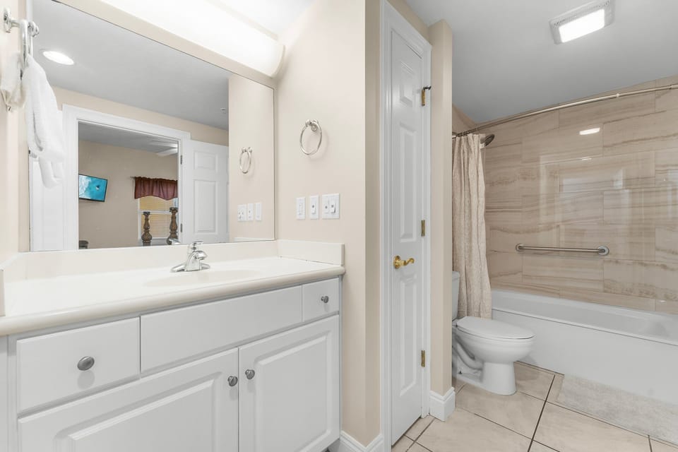 Clean bathroom with a large mirror and bathtub with shower curtain.