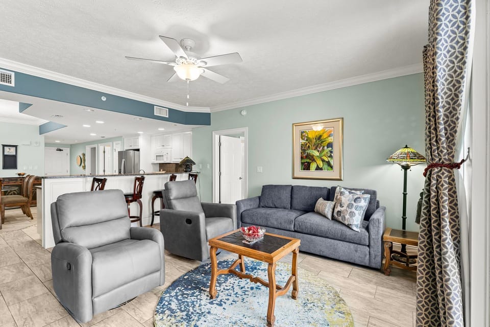 Casual living space w/ ceiling fan & soft tones — great for lounging after a beach day.
