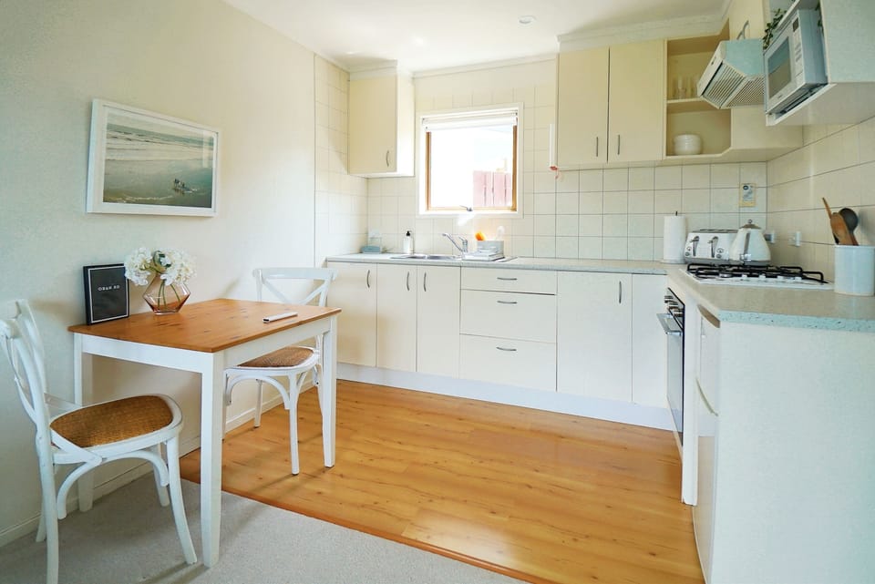 Kitchen with stove, jug, microwave, seating and natural sunlight