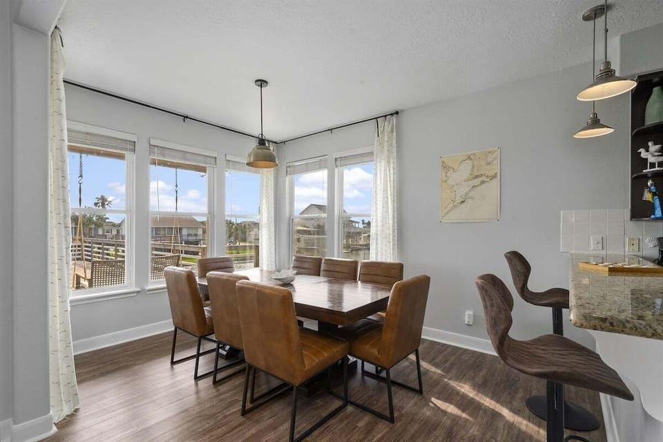 Dining area with wood table, pendant lighting, bright windows, canal views, and easy access to the open living space.