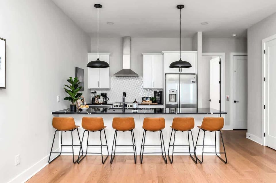 Stylish white kitchen with stainless appliances and a large island for six.