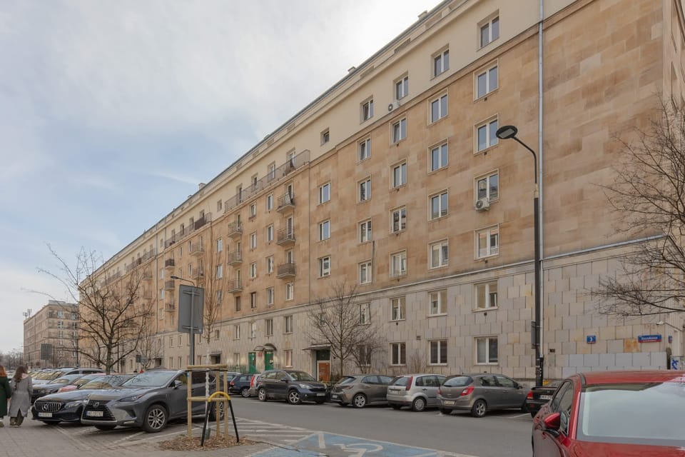 Another angle of the building, showcasing its urban location and parking area.

