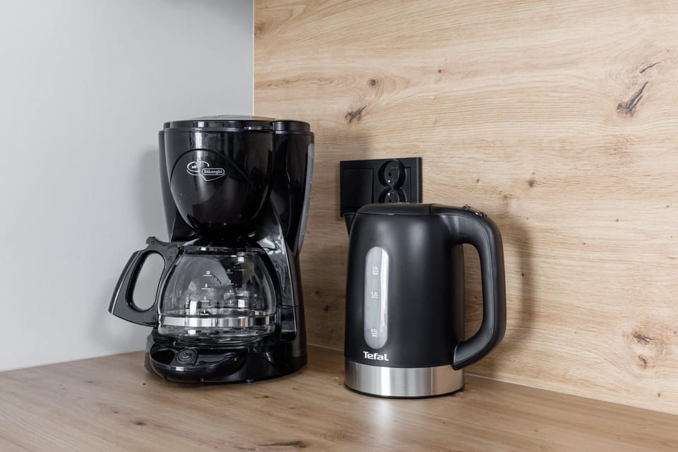 A kitchenette equipped with modern appliances, including a coffee maker and kettle. The wooden accents add warmth to the design.