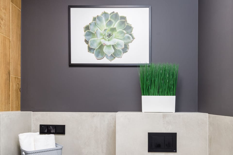 A decorative wall-mounted piece featuring green and white tones. A plant adds a natural touch below the artwork.