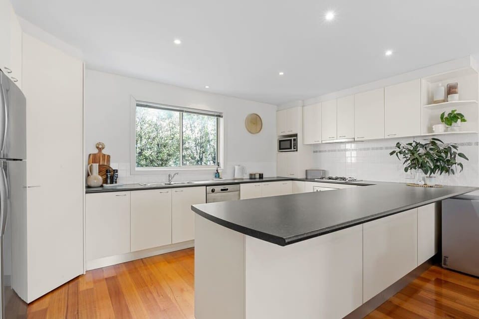 The functional kitchen boasts a full suite of appliances, ample storage, and a breakfast bar for casual meals