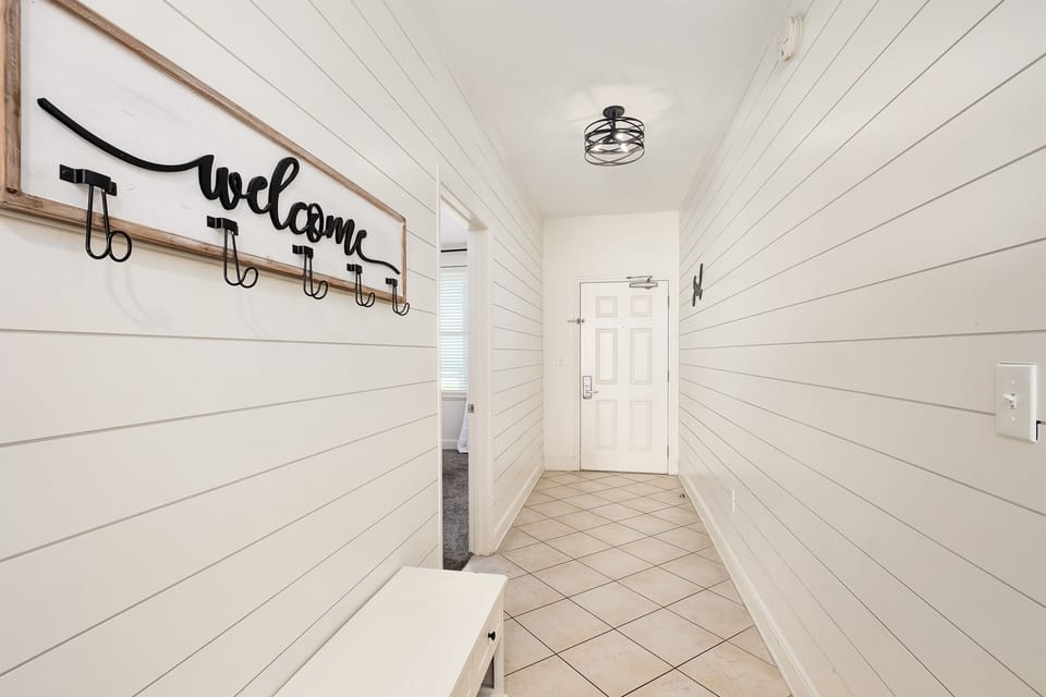 Step into your welcoming entryway where bright white shiplap walls and thoughtful hooks invite you to settle in and feel at home.