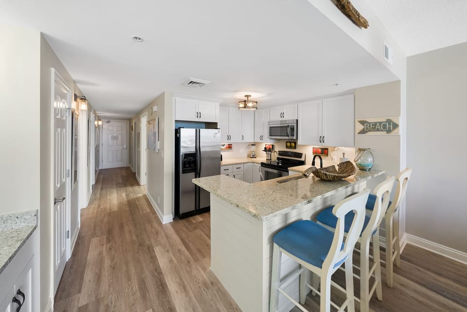 Your fully equipped kitchen awaits with granite counters, stainless appliances, and coastal charm for memorable meal prep.