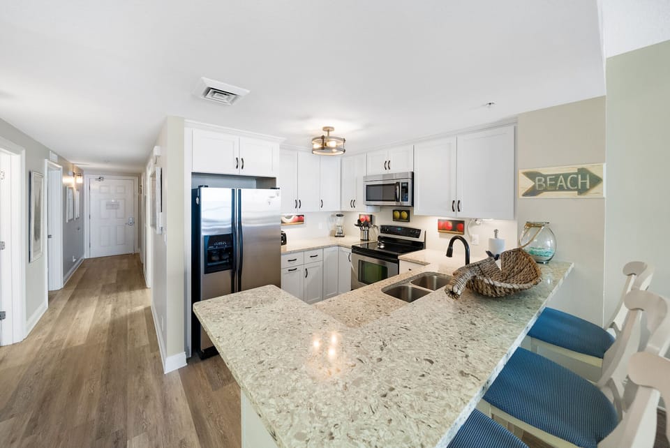 Your fully equipped kitchen awaits with granite counters, stainless appliances, and coastal charm for memorable meal prep.