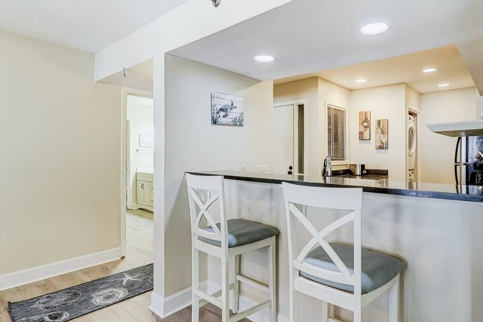 Bar stools across from dining room table and have view of friends in living room